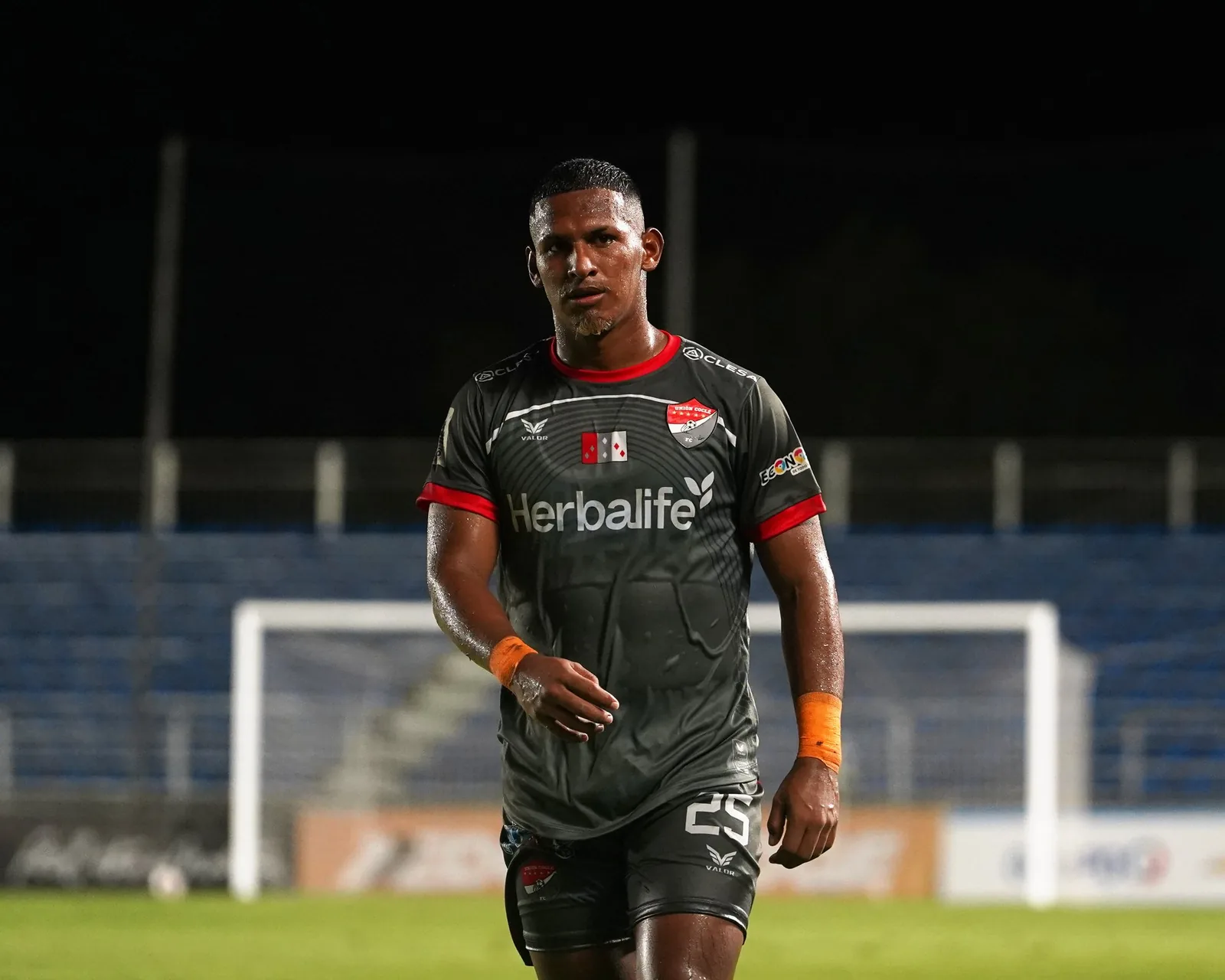Futbolista caminando hacia la cámara en un estadio de noche